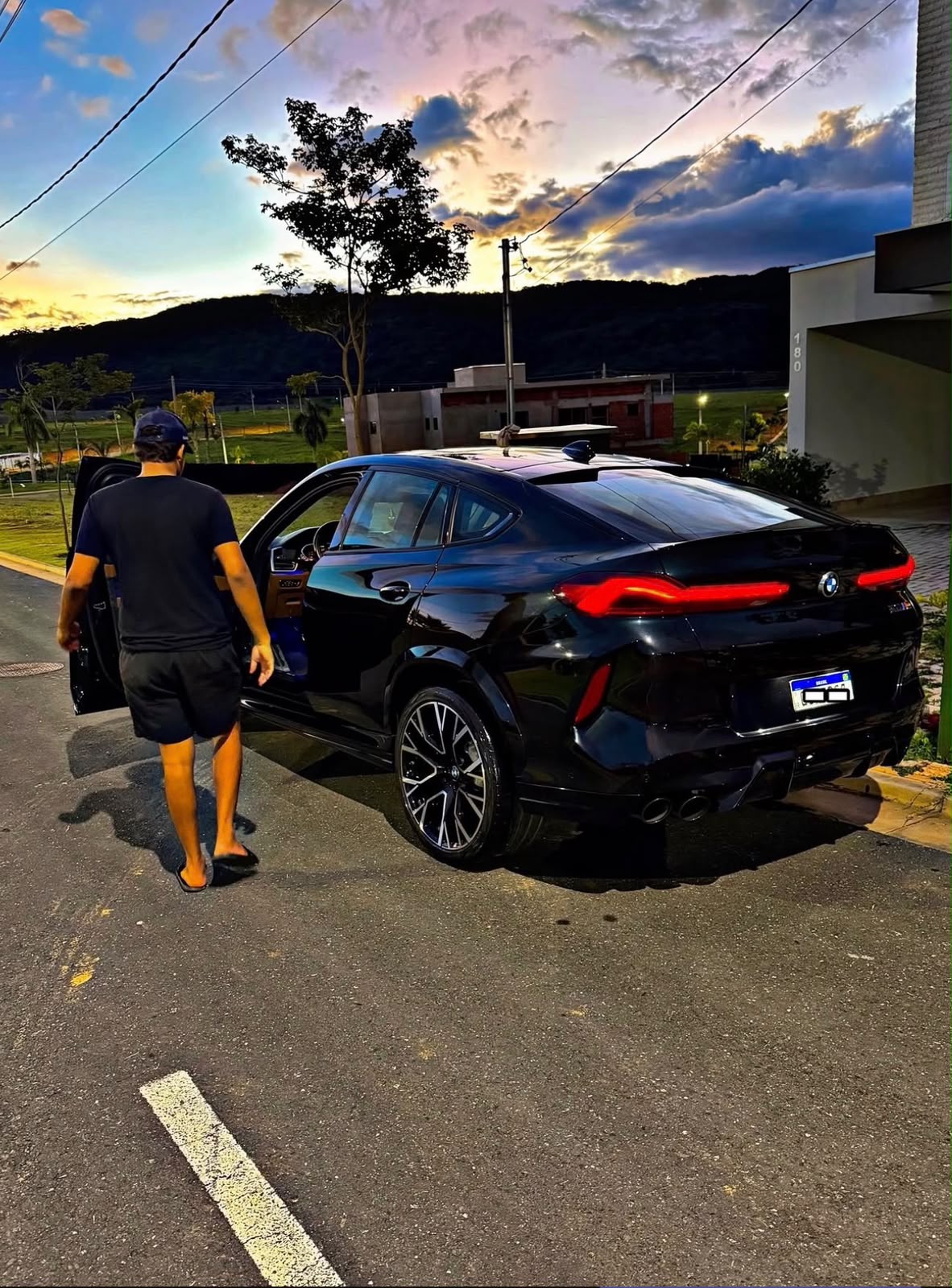 Lucas Andrey ao lado da BMW X6 M no pôr do sol